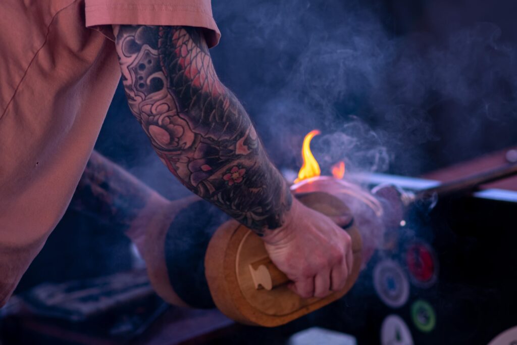 A person with tattoos holding onto a fire