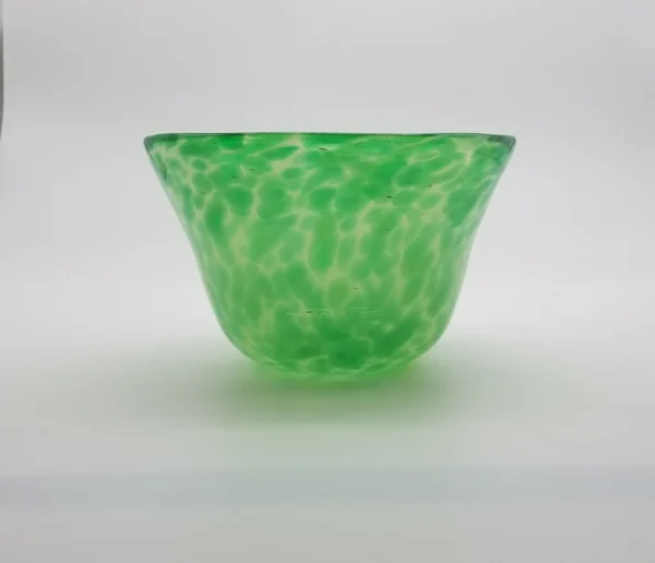 A green glass bowl sitting on top of a table.