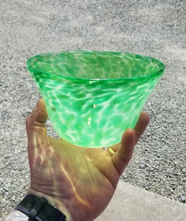 A person holding a green glass bowl in their hand.