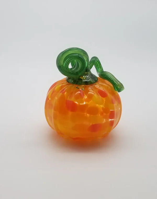 A glass pumpkin with green stem and orange dots.