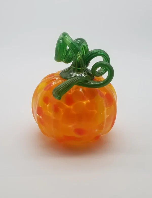 A glass pumpkin with green stem and leaves.