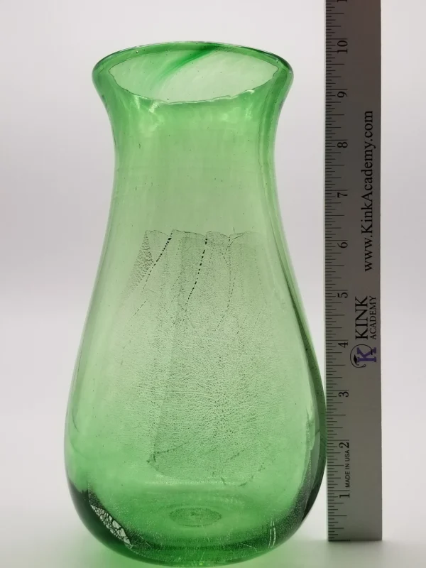 A green vase with a ruler and some water