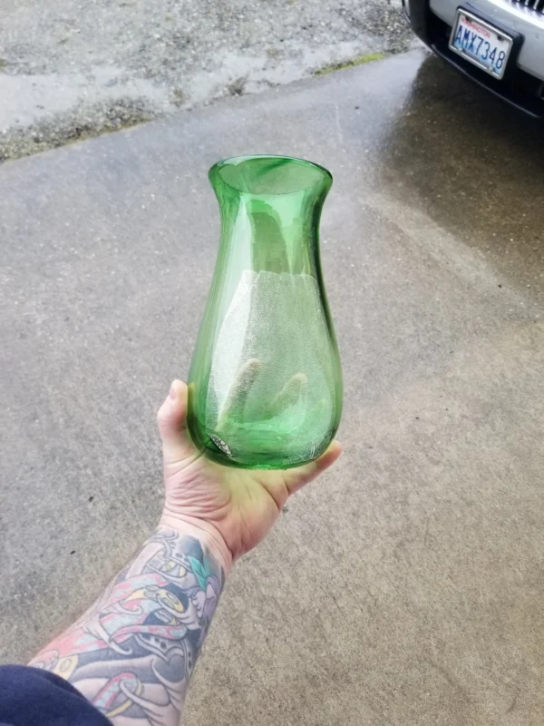 A person holding a green vase in their hand.
