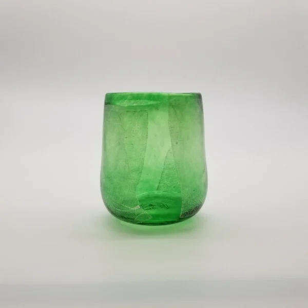 A green glass cup sitting on top of a table.