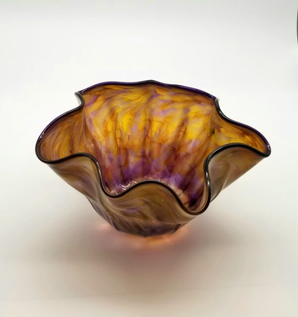 A glass bowl with a purple and yellow design.
